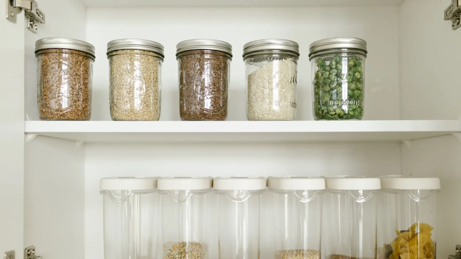 Cabinet shelves with matching jars and clear canisters of grains, lentils and pasta