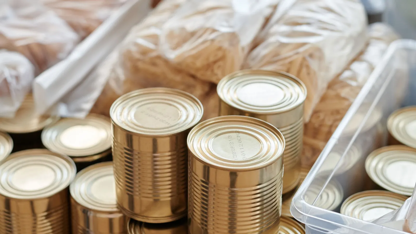 Stacked unlabeled cans in front of packaged bread and bottled water
